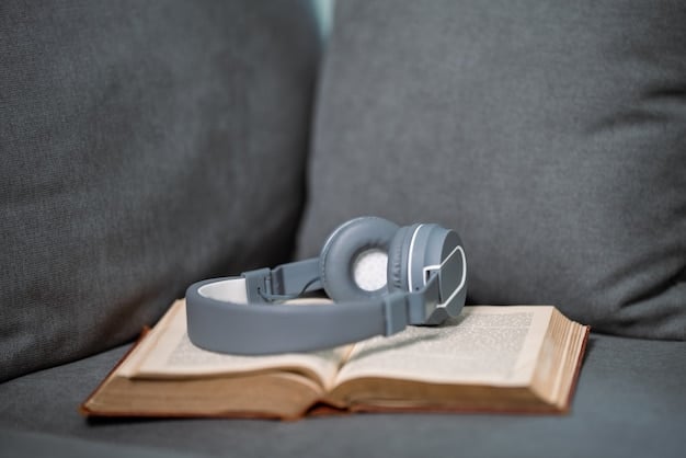 A close-up of headphones resting on a desk, surrounded by books and a notebook. The headphones are a prominent feature, emphasizing their role in listening to binaural beats for focus and relaxation.