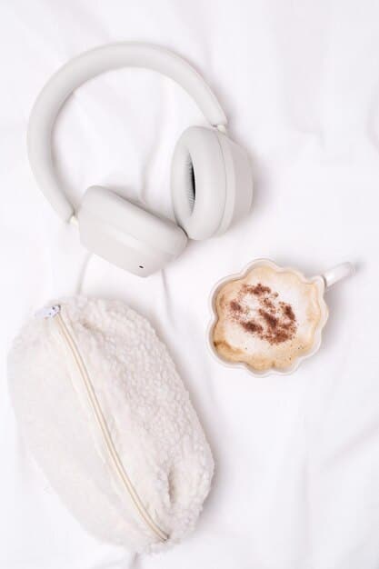 A close-up shot of the earcups of noise-canceling headphones, highlighting the plush padding and ergonomic design, resting on a minimalist desk with a blurred background.