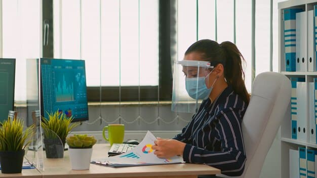 A person wearing a brain-sensing headband while working on a computer, with a graph on the screen showing their brain activity and focus levels. The setting is a modern, well-lit office.